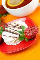 lemon tea, cake and strawberries lying on the orange fabric