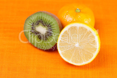 kiwi,lemon,mandarin  lying on the orange fabric