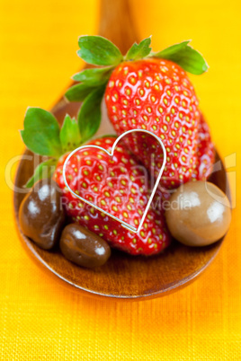 strawberry, hearts and chocolate candy in the wooden spoon of th