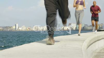 Three friends running near the sea in Havana, Cuba