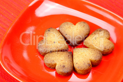cookie  in the form of heart  in a plate  on a red background
