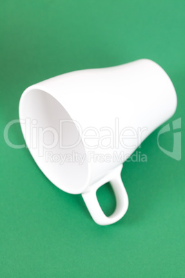 white cup lying on a green background