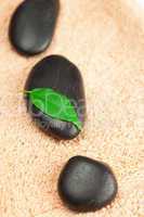 black spa stones  with green leaf and a drop of water on the tow