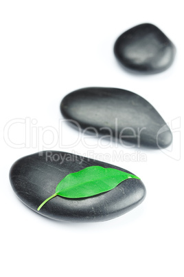 black spa stones   with green leaf and a drop of water isolated