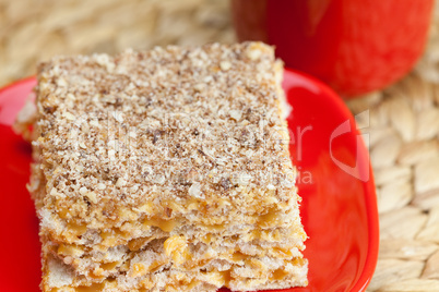 cake on a plate and a cup of coffee on a wicker mat