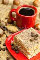 cake on a plate, nuts and a cup of coffee on a wicker mat