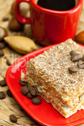 cake on a plate, nuts and a cup of coffee on a wicker mat