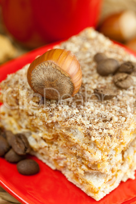 cake on a plate, nuts and a cup of coffee on a wicker mat