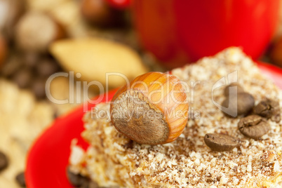 cake on a plate, nuts and a cup of coffee on a wicker mat