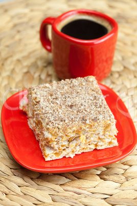 cake on a plate and a cup of coffee on a wicker mat