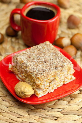 cake on a plate, nuts and a cup of coffee on a wicker mat