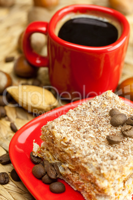 cake on a plate, nuts and a cup of coffee on a wicker mat