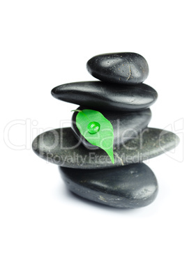 black spa stones   with green leaf and a drop of water isolated