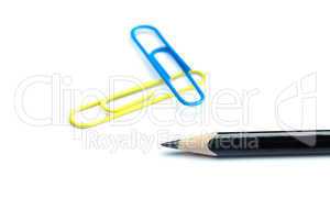 black pencil and colored paper clip isolated on white