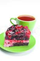 beautiful cake with berries on a plate and a cup of tea isolated