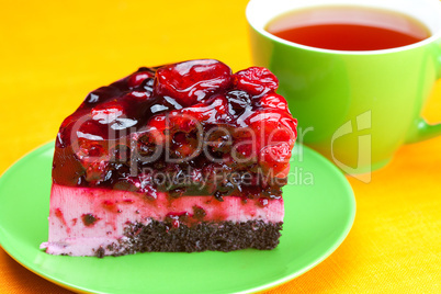 beautiful cake with berries on a plate and a cup of tea on the o