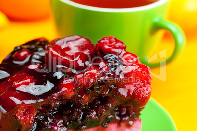 beautiful cake with berries on a plate and a cup of tea on the o