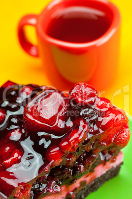 beautiful cake with berries on a plate and a cup of tea on the o