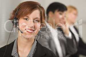 Pretty Red Haired Businesswoman with Headset and Colleagues