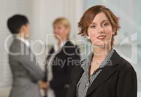Pretty Red Haired Businesswoman with Colleagues Behind