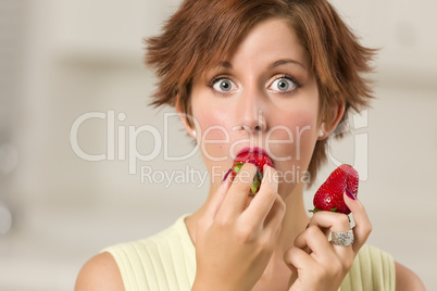 Pretty Wide-eyed Red Haired Woman Biting Strawberry
