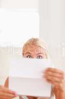Shocked blond woman reading a letter