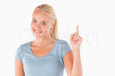 Blond woman pointing at copyspace looking into the camera