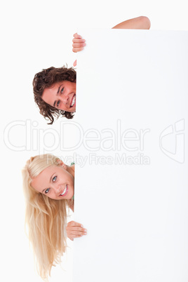 Couple hiding behind a whiteboard