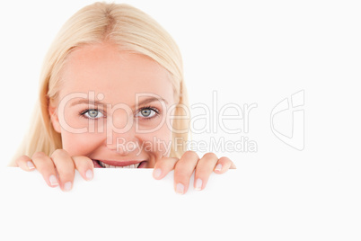 Smiling woman peeking over a whiteboard