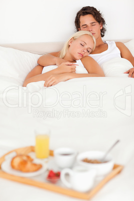 Couple sleeping with the breakfast served on a tray