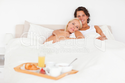 Smiling couple with the breakfast put on a tray