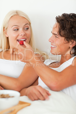 Portrait of a cute man giving a strawberry to his girlfriend