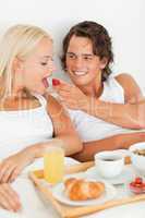 Portrait of handsome man giving a strawberry to his girlfriend