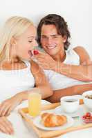 Portrait of smiling man giving a strawberry to his girlfriend