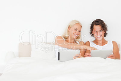 Laughing couple using tablet computers