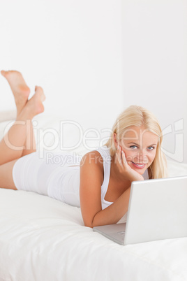 Portrait of a woman using a laptop on her bed