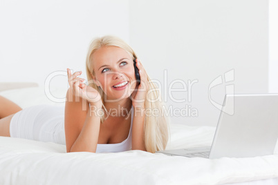Smiling woman speaking to the phone with a laptop