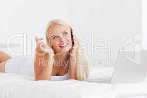Smiling woman speaking to the phone with a laptop