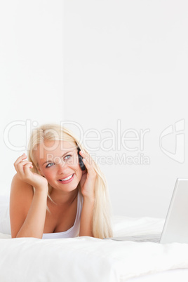 Portrait of a woman speaking to the phone with a laptop
