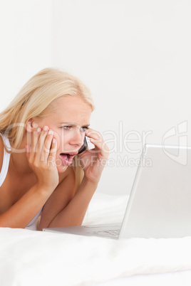 Portrait of an upset woman on the phone while using a laptop