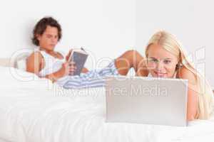 Woman using a laptop while her fiance is reading