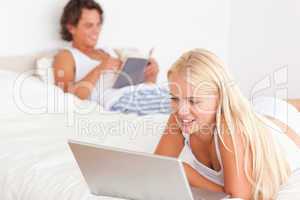 Woman using a notebook while her fiance is reading