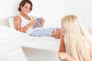 Woman with a laptop while her fiance is reading