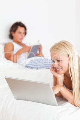 Portrait of a woman using a notebook while her fiance is reading