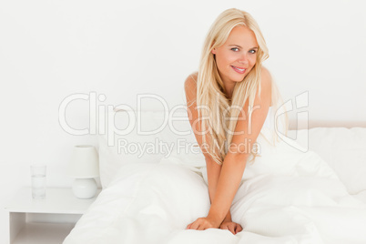 Blonde woman sitting on her bed