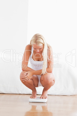 Portrait of a fit woman squatting on a weighing machine