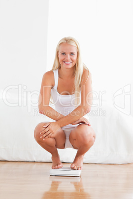Portrait of a woman squatting on a weighing machine