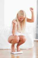 Portrait of a sportive woman squatting on a weighing machine