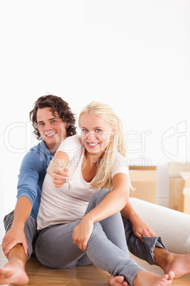 Portrait of a cute woman sitting with her boyfriend giving keys