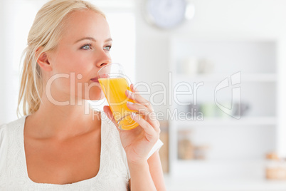 Close up of a blonde woman drinking juice